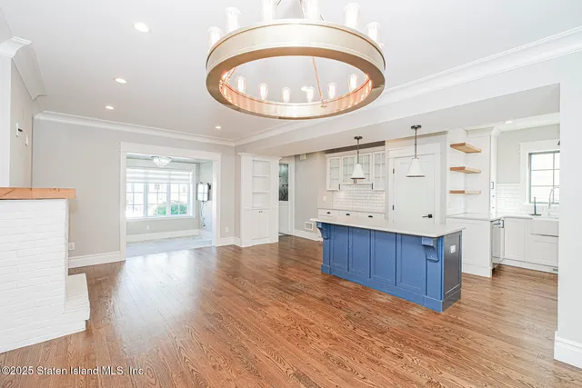 an empty room with wooden floor cabinet and windows