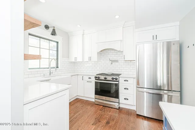 a kitchen with stainless steel appliances a refrigerator sink and wooden floor