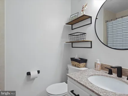 a bathroom with a granite countertop toilet sink mirror and vanity