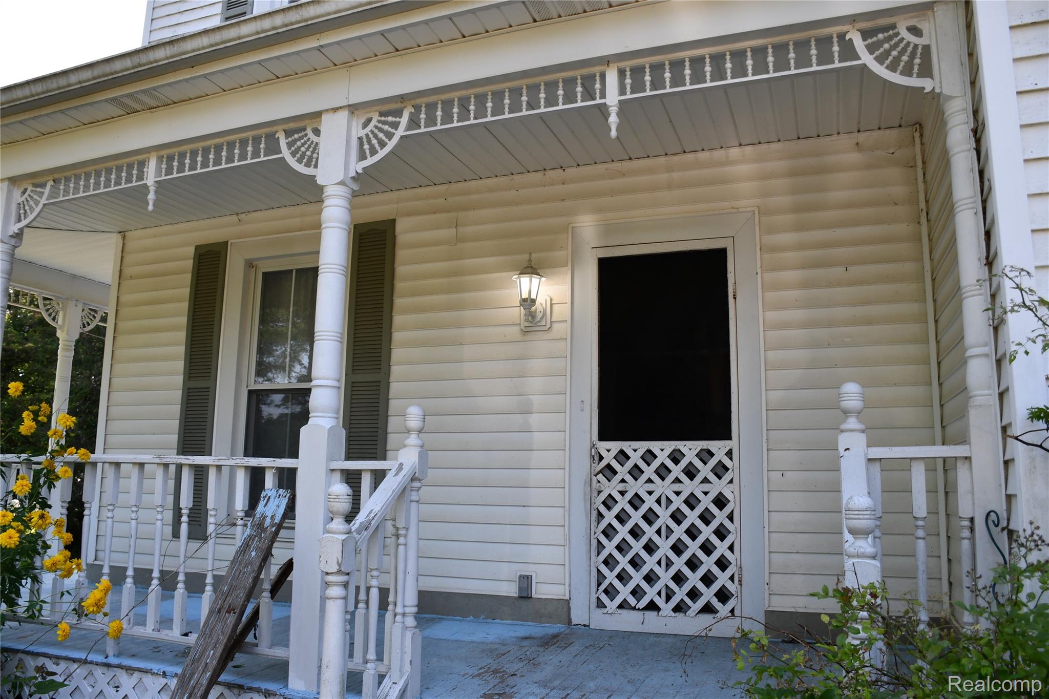 5245 East Clyde Road Howell, MI 48855 - Photo 9 of 28 Front porch featuring decorative spindle work, a wooden railing, and a lattice screen door