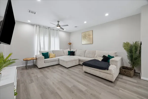 a living room with furniture a flat screen tv and a potted plant