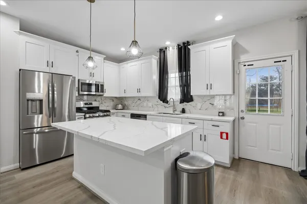 a kitchen with stainless steel appliances granite countertop a sink a stove a refrigerator and island with wooden floor