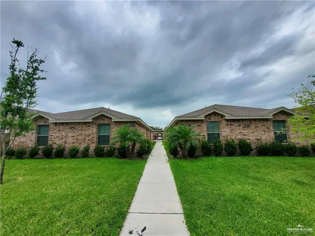 a view of house in front of a big yard with large trees