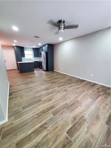 an empty room with wooden floor and a ceiling fan