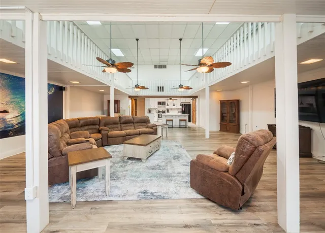 a living room with furniture kitchen view and a chandelier