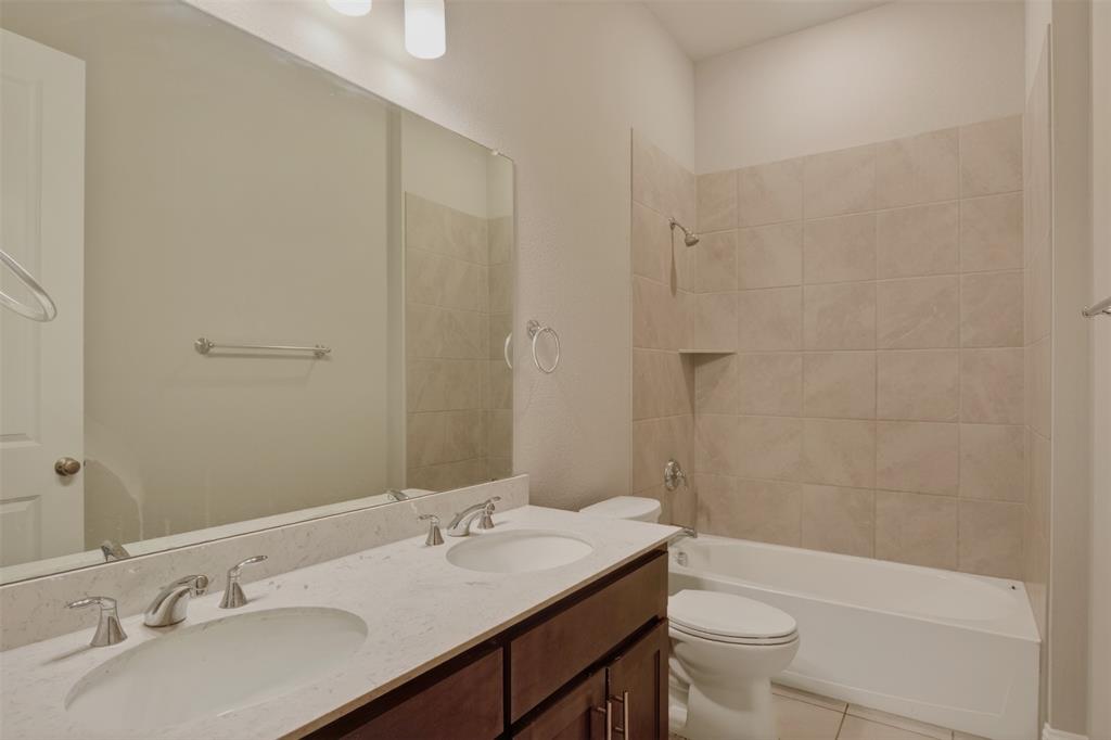 16812 Bitterroot Road Justin, TX 76247 - Photo 11 of 27 a bathroom with a granite countertop sink toilet a large mirror a shower and a bathtub