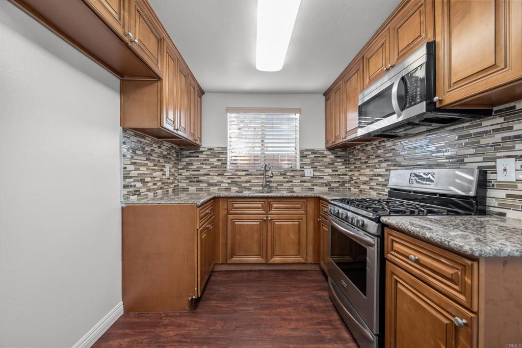 5120 North River Road, Unit E Oceanside, CA 92057 - Photo 2 of 13 a kitchen with stainless steel appliances granite countertop a stove a sink and a microwave