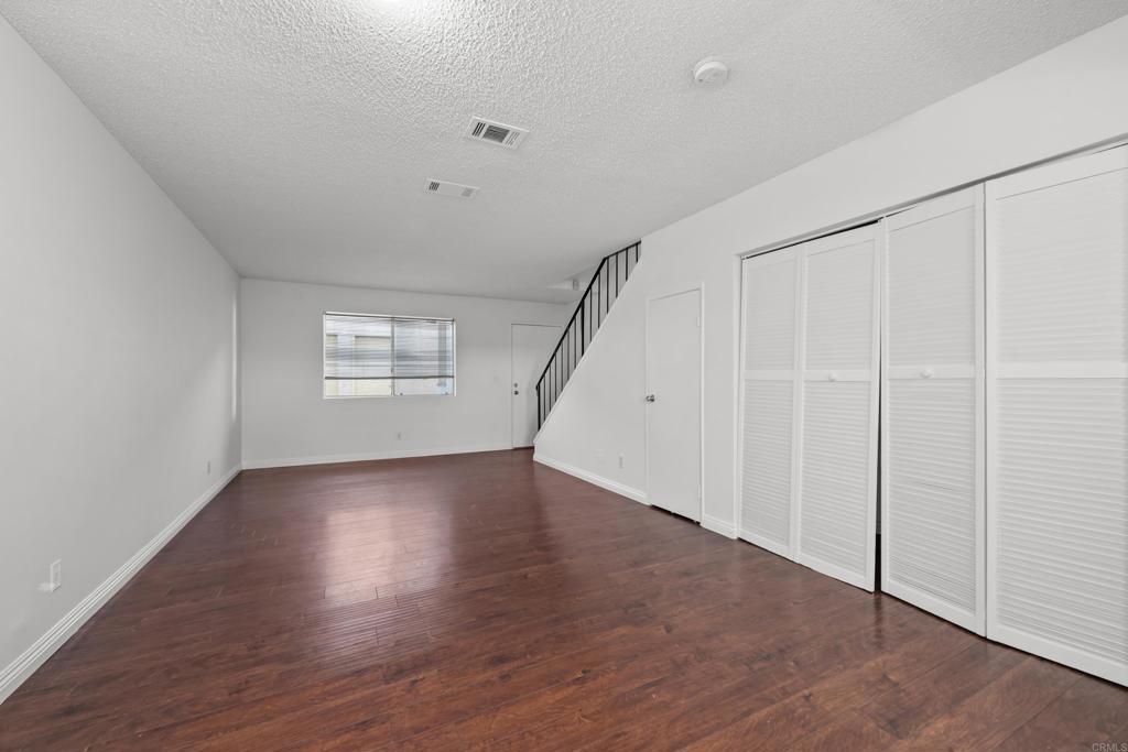 5120 North River Road, Unit E Oceanside, CA 92057 - Photo 5 of 13 an empty room with wooden floor and windows