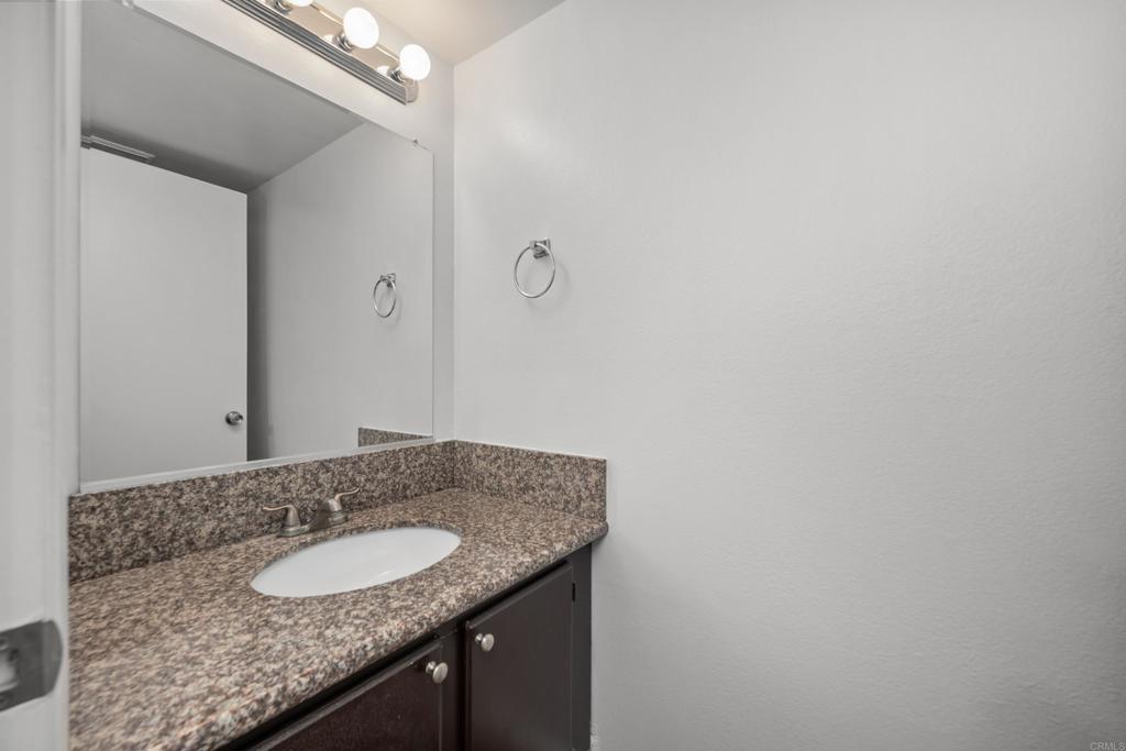 5120 North River Road, Unit E Oceanside, CA 92057 - Photo 6 of 13 a bathroom with a granite countertop sink and a mirror