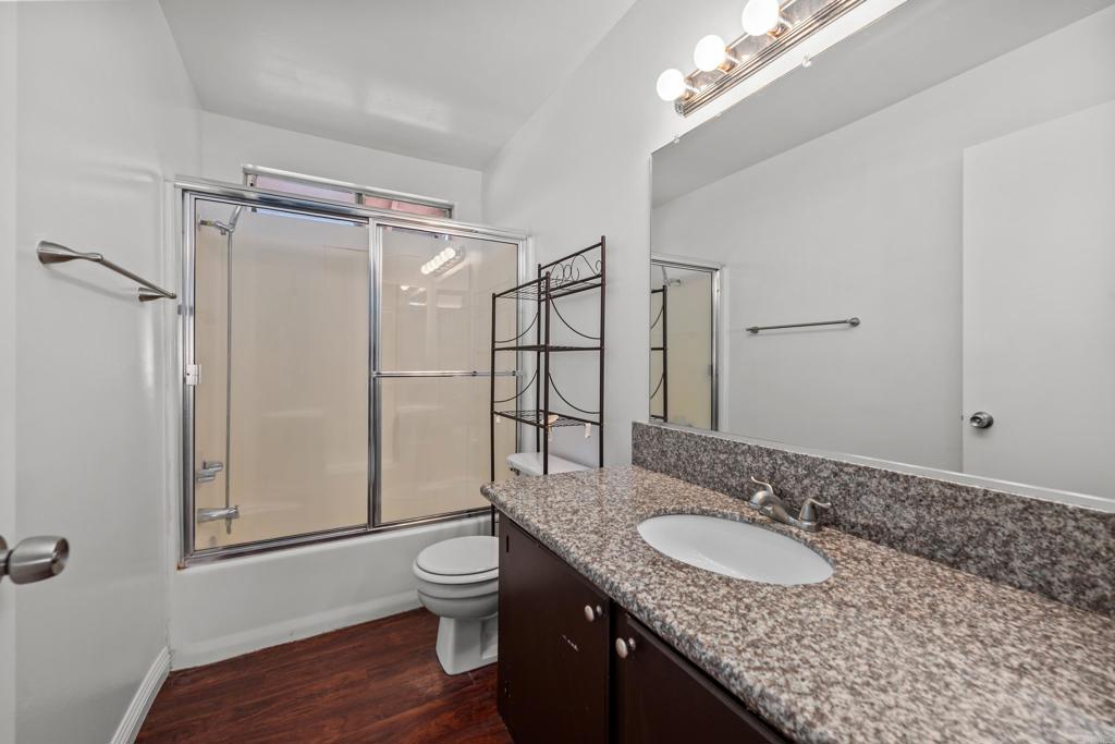 5120 North River Road, Unit E Oceanside, CA 92057 - Photo 7 of 13 a bathroom with a granite countertop sink a toilet a mirror and shower