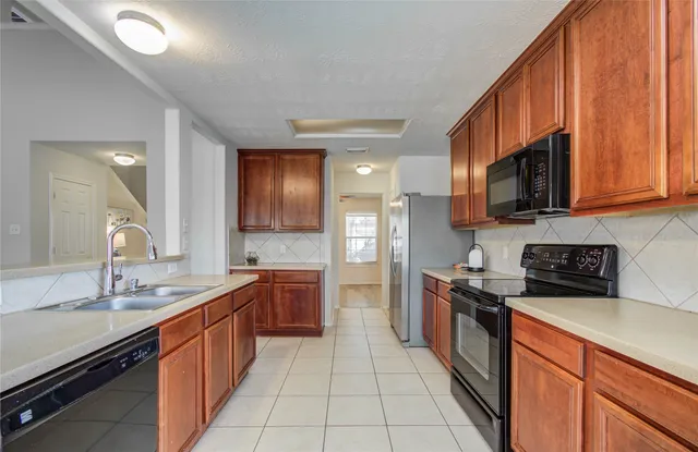 a large kitchen with stainless steel appliances granite countertop a sink stove and cabinets