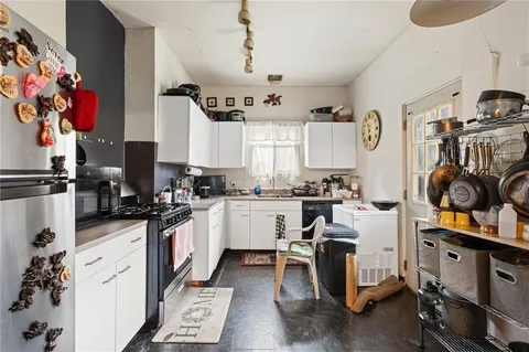 a kitchen with white cabinets and appliances