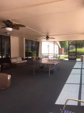 a living room with furniture a floor to ceiling window and a kitchen view