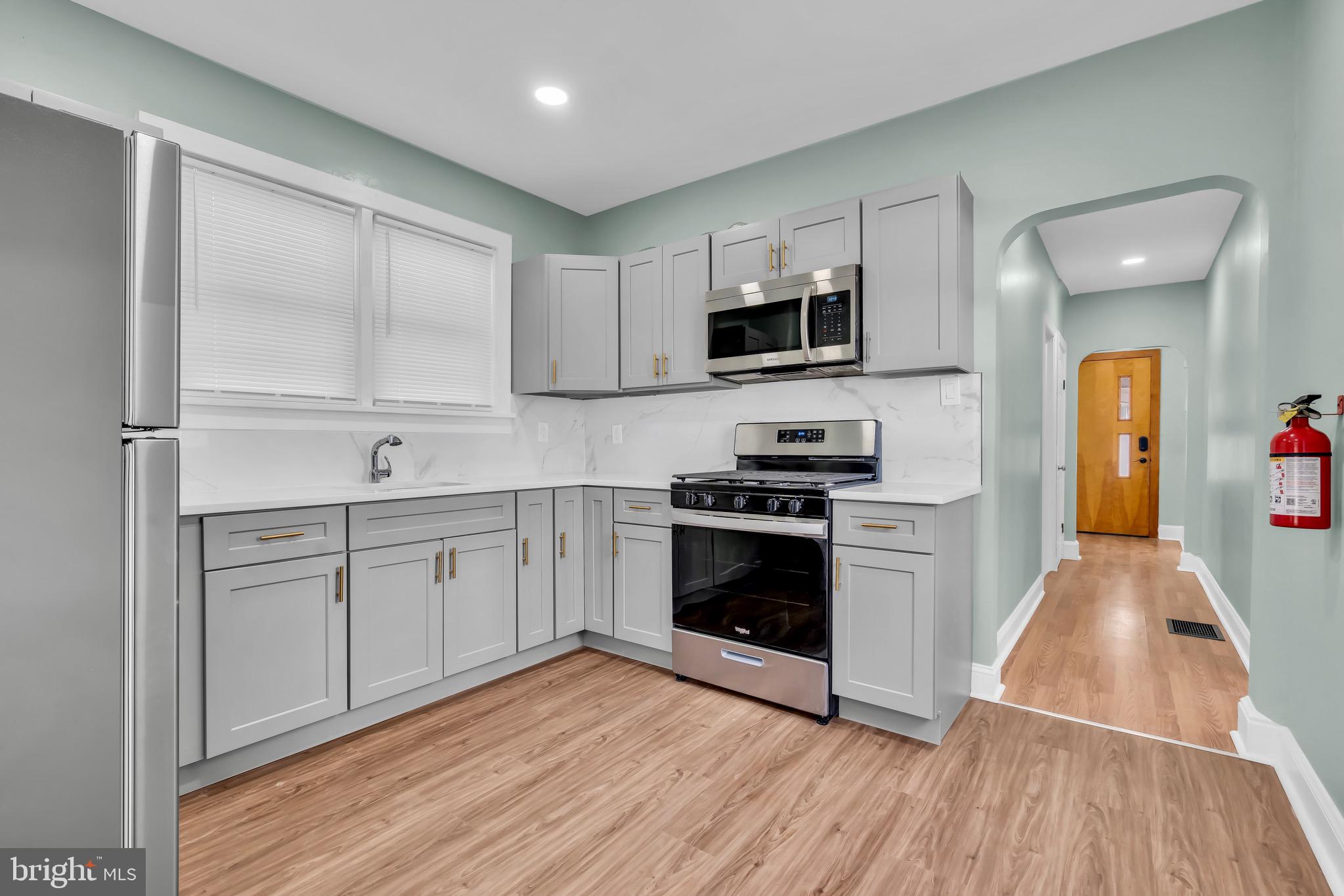 127 Cleveland Avenue Riverside, NJ 08075 - Photo 2 of 7 a kitchen with stainless steel appliances a stove top oven a sink a refrigerator white cabinets and wooden floor