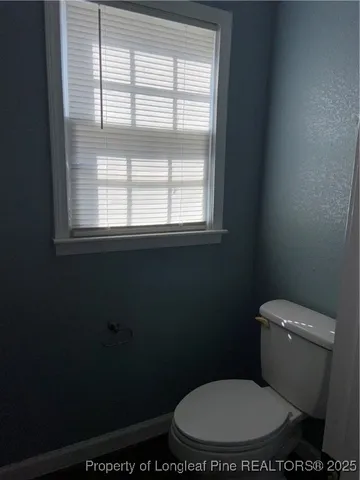 a white toilet sitting in a bathroom next to a window