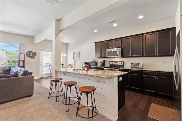 a kitchen with stainless steel appliances granite countertop a stove top oven a sink and dishwasher with wooden floor