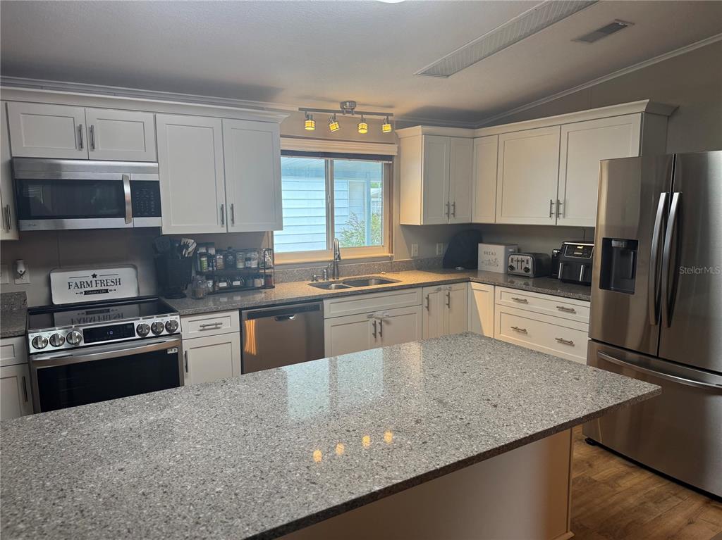 1001 Starkey Road, Unit 310 Largo, FL 33771 - Photo 6 of 25 a kitchen with granite countertop a sink stainless steel appliances and white cabinets
