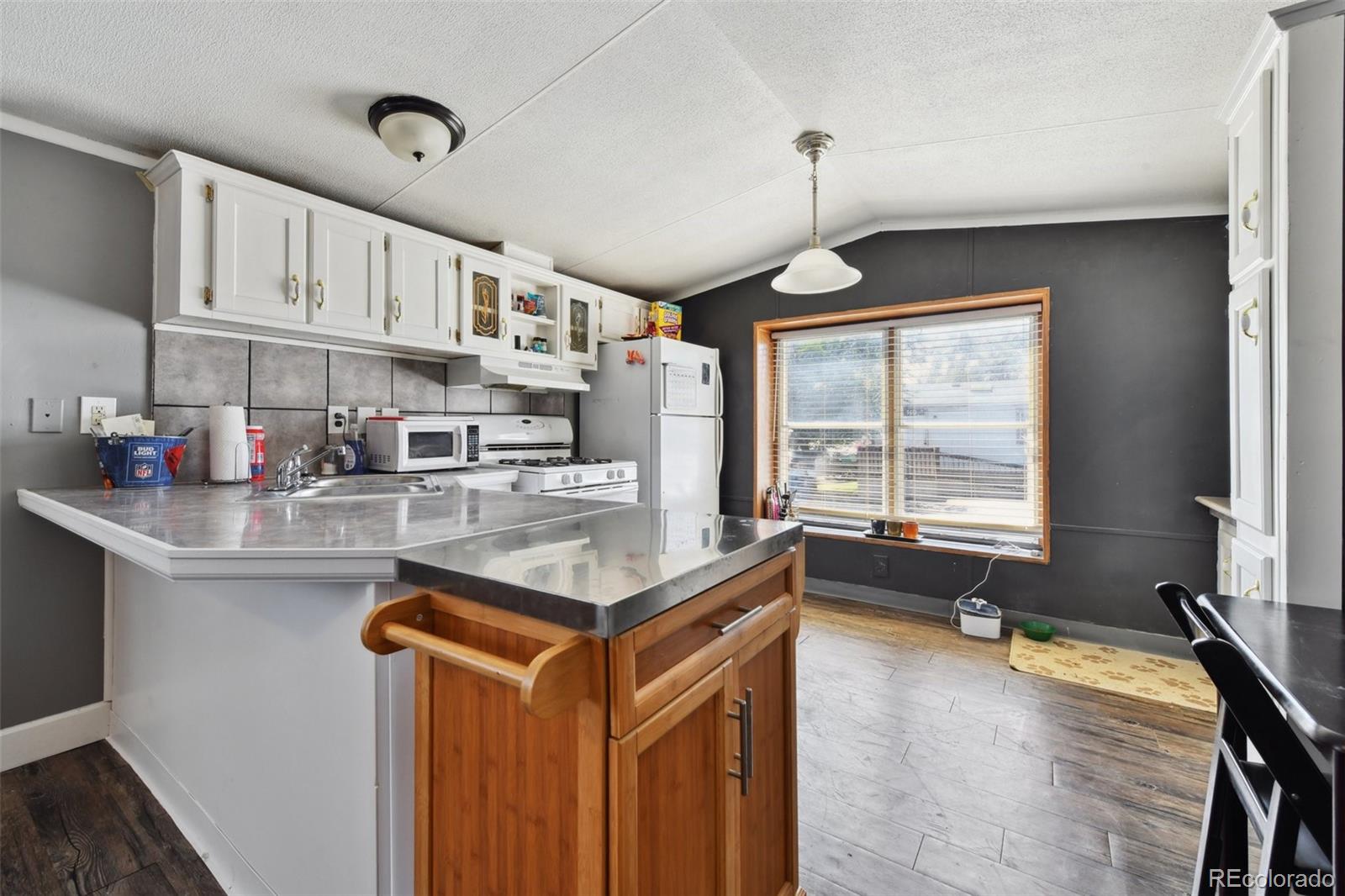 9400 North Elm Court Denver, CO 80260 - Photo 3 of 23 a kitchen with kitchen island granite countertop a sink appliances cabinets and a counter top space