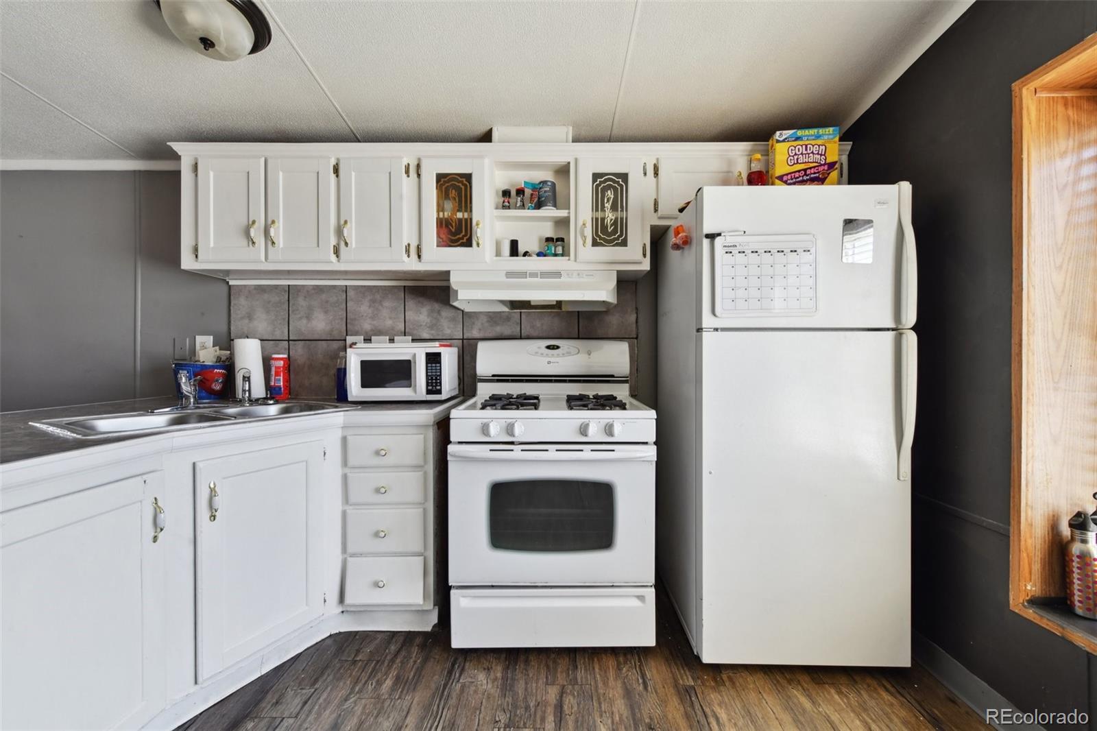 9400 North Elm Court Denver, CO 80260 - Photo 6 of 23 a white refrigerator freezer sitting inside of a kitchen with stainless steel appliances granite countertop wooden floor sink and cabinets