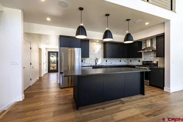 a view of a kitchen with a sink a refrigerator and wooden floor
