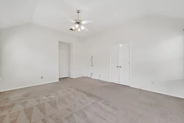 a view of an empty room with a chandelier fan