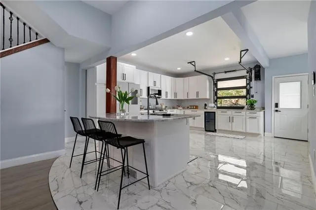 a kitchen with stainless steel appliances kitchen island granite countertop a table chairs sink and cabinets