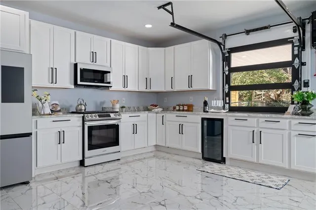 a kitchen with white cabinets appliances and a window