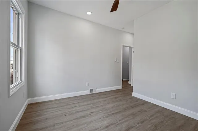 an empty room with wooden floor cabinet and windows