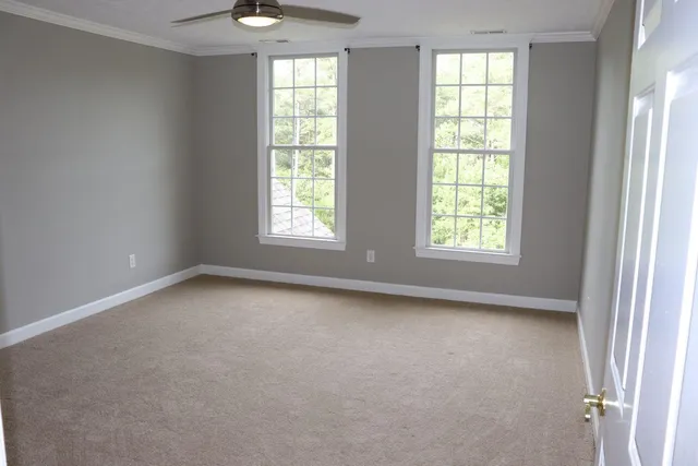 an empty room with windows and chandelier fan