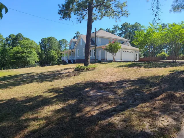 a front view of a house with a yard and trees