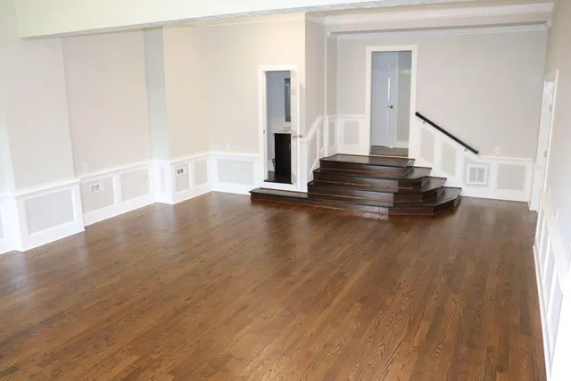 a view of an empty room with wooden floor and stairs