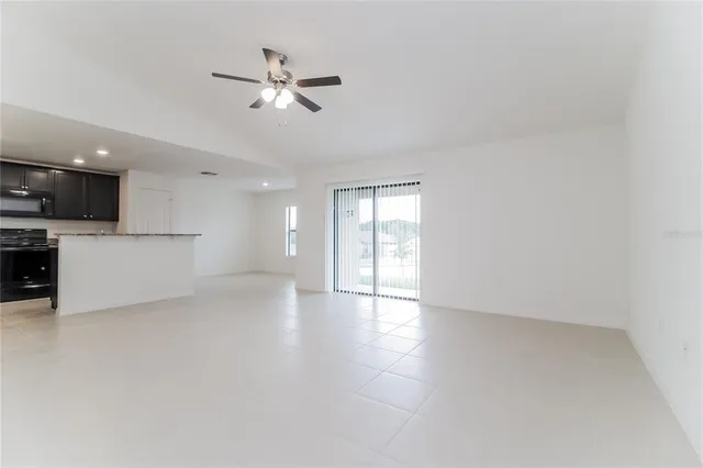 a view of a livingroom with a ceiling fan and kitchen space