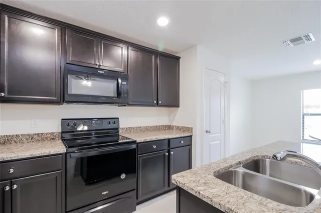 a kitchen with granite countertop a sink a stove and cabinets
