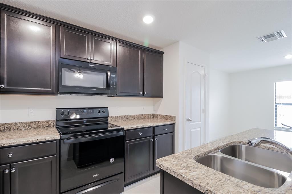 1187 Moyle Way Mascotte, FL 34753 - Photo 5 of 16 a kitchen with granite countertop stainless steel appliances a sink stove and microwave