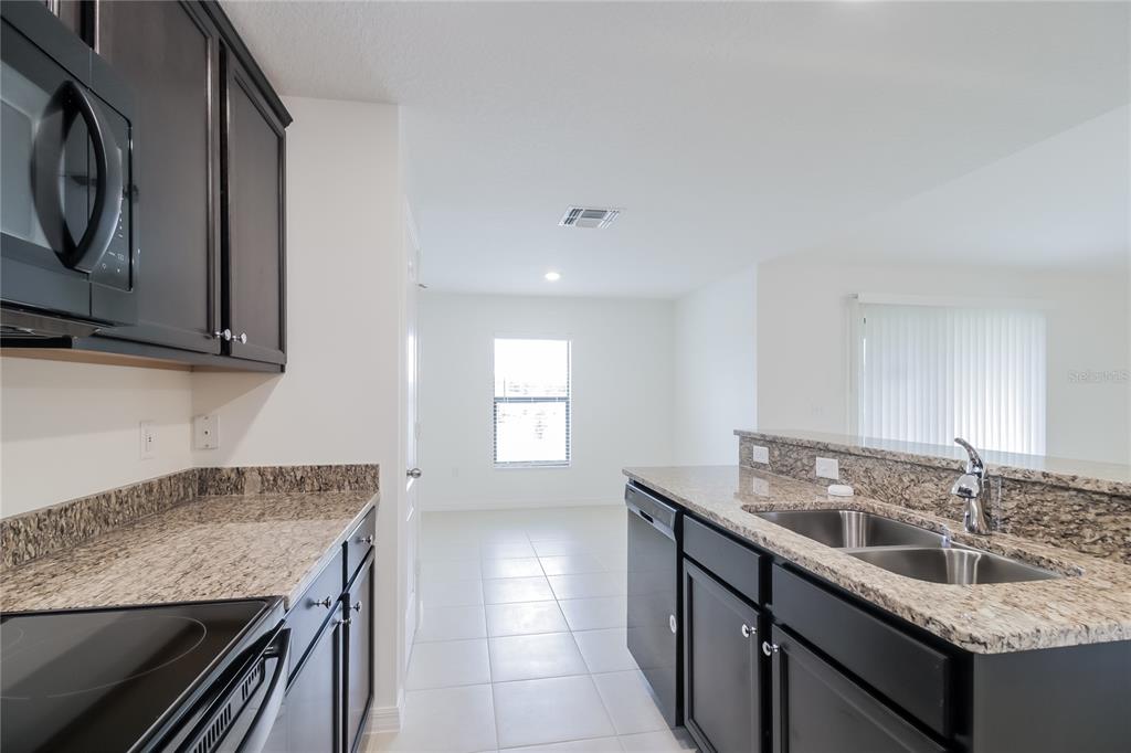 1187 Moyle Way Mascotte, FL 34753 - Photo 6 of 16 a kitchen with granite countertop a sink a stove and cabinets