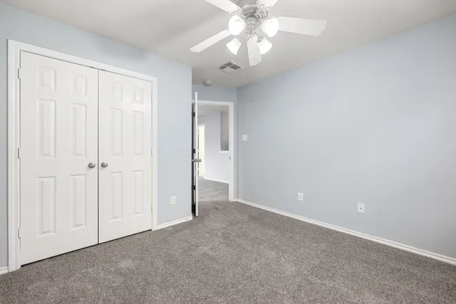 an empty room with a chandelier fan and windows
