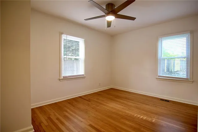 a view of empty room with wooden floor and fan