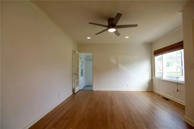 an empty room with wooden floor fan and windows