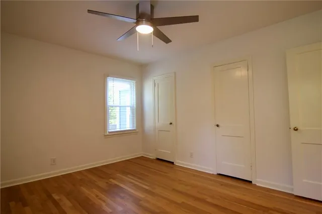 an empty room with wooden floor fan and windows