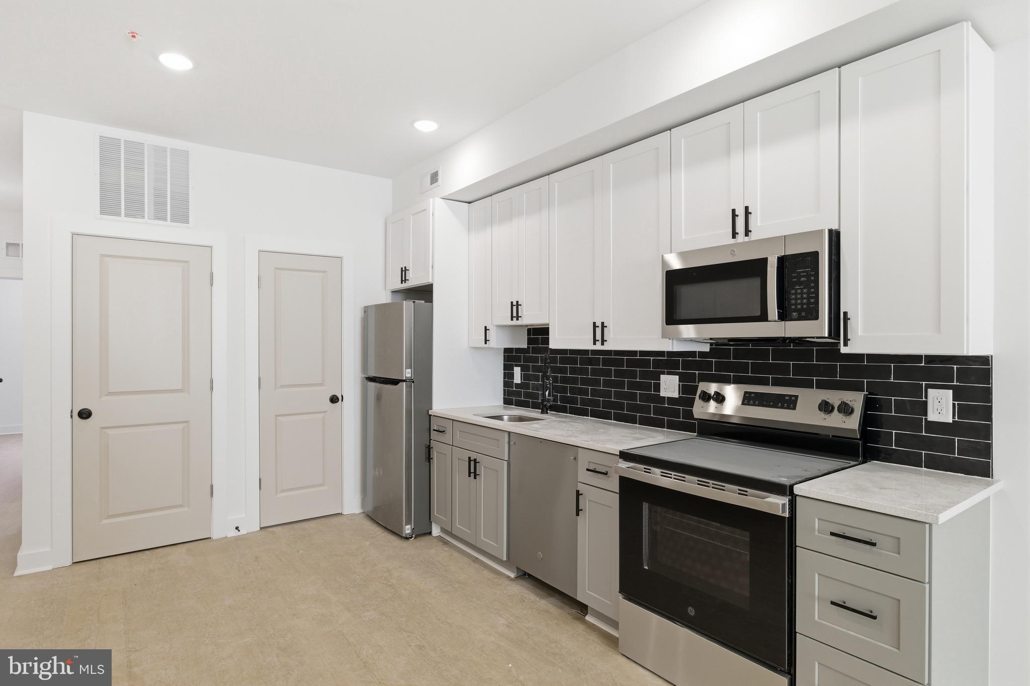 2116 North 7th Street, Unit 2 Philadelphia, PA 19122 - Photo 1 of 21 a kitchen with stainless steel appliances a stove a microwave and white cabinets