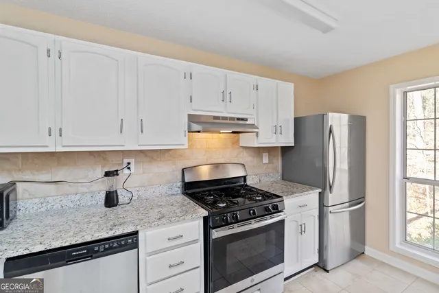 a kitchen with white cabinets and stainless steel appliances