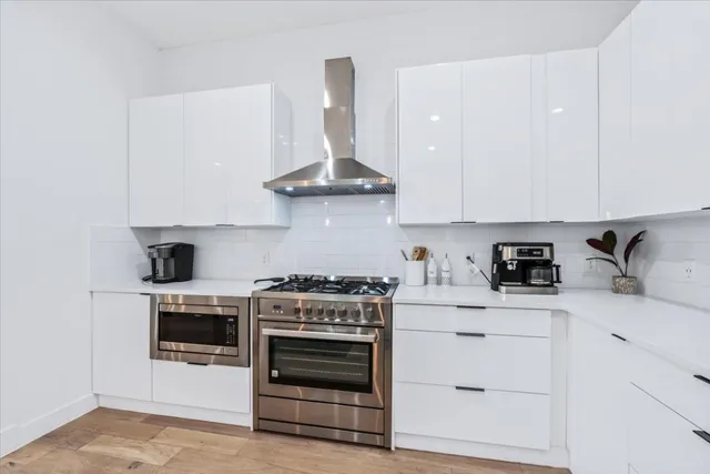 a kitchen with stainless steel appliances granite countertop a stove and white cabinets