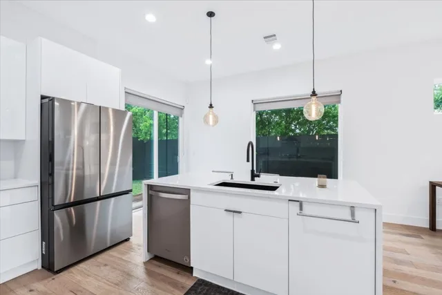 a kitchen with stainless steel appliances granite countertop a refrigerator a sink and a stove with wooden floor