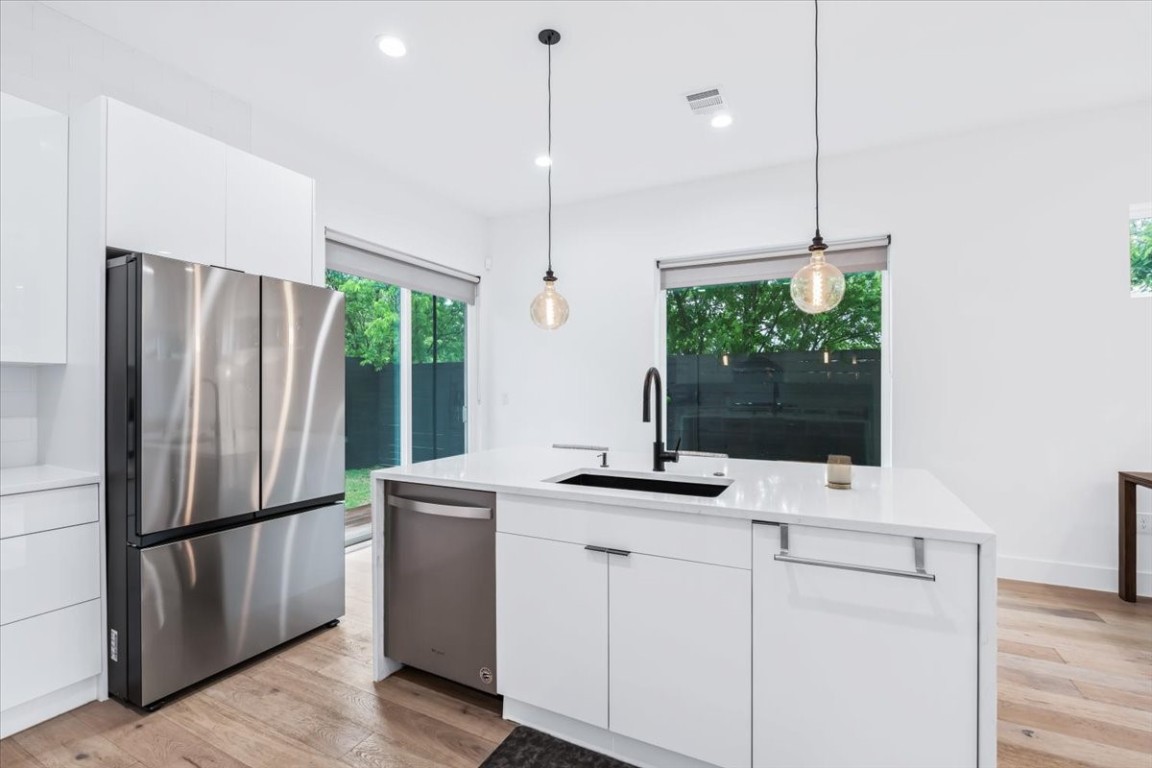 6300 Santos Street, Unit 3 Austin, TX 78741 - Photo 14 of 32 a kitchen with stainless steel appliances granite countertop a refrigerator a sink and a stove with wooden floor