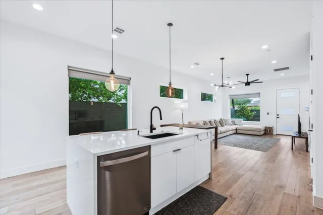 a kitchen with stainless steel appliances granite countertop a sink a stove and a wooden floors