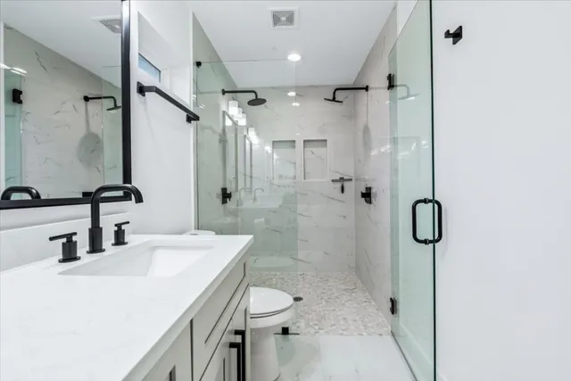 a bathroom with a granite countertop sink a toilet and shower