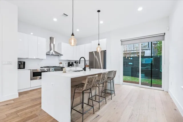 a kitchen with stainless steel appliances kitchen island a large island a stove a refrigerator and a wooden floors