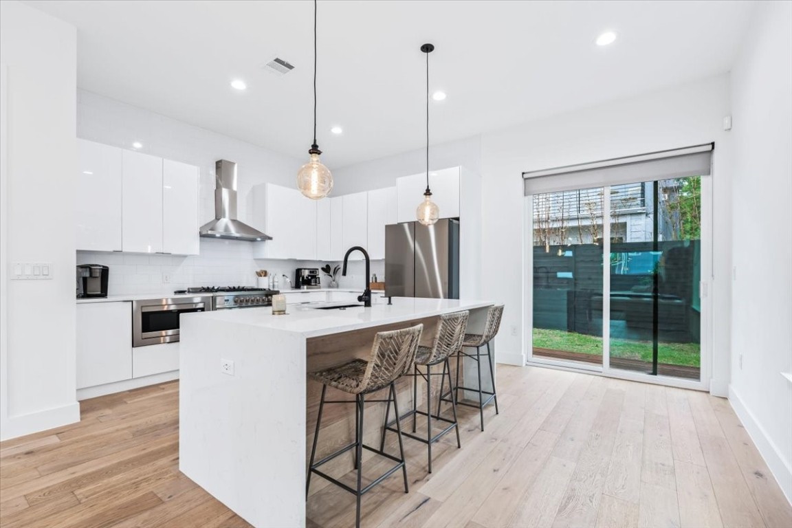 6300 Santos Street, Unit 3 Austin, TX 78741 - Photo 8 of 32 a kitchen with stainless steel appliances kitchen island a large island a stove a refrigerator and a wooden floors