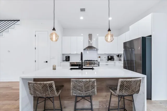 a kitchen with stainless steel appliances kitchen island granite countertop a table chairs and a refrigerator