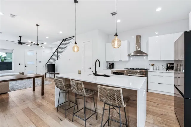 a kitchen with stainless steel appliances granite countertop a sink a stove and a wooden floors